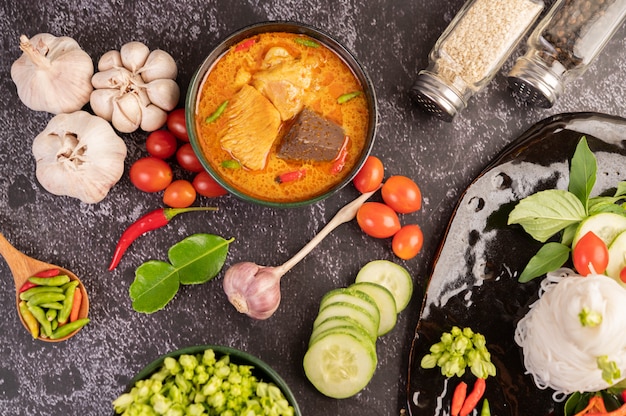 Curry di pollo in una tazza nera con spaghetti di riso.