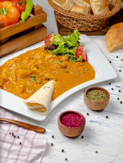 Curry indiano con petto di pollo e salsa di pomodoro servito con lavash.