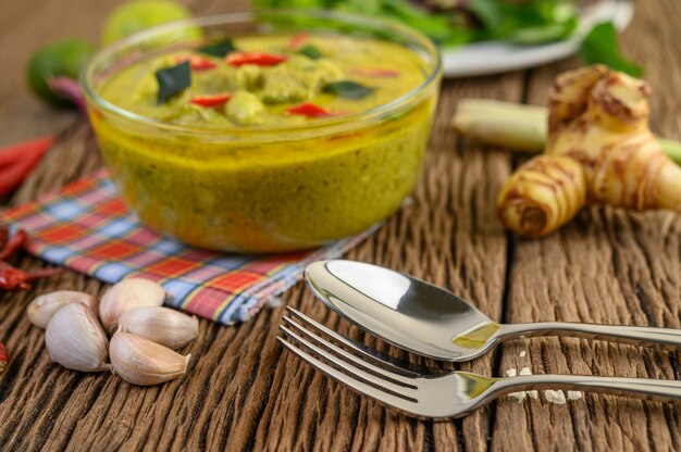 Curry verde in una ciotola con la forchetta e cucchiaio sulla tavola di legno.