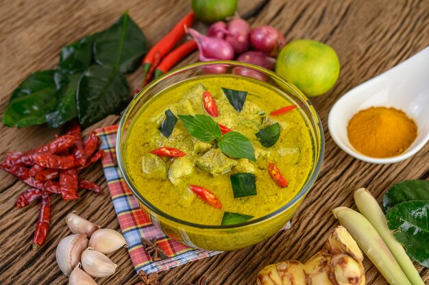 Curry verde in una ciotola e spezie sulla tavola di legno.