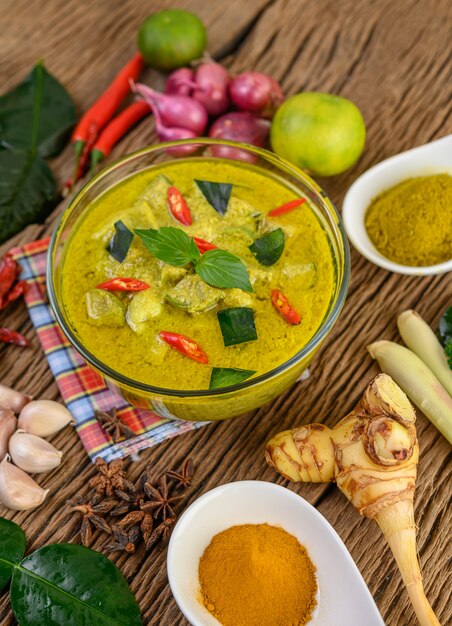Curry verde in una ciotola e spezie sulla tavola di legno.