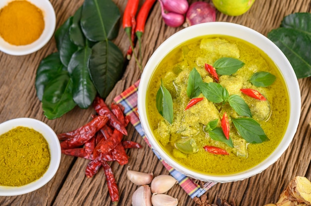 Curry verde in una ciotola e spezie sulla tavola di legno.