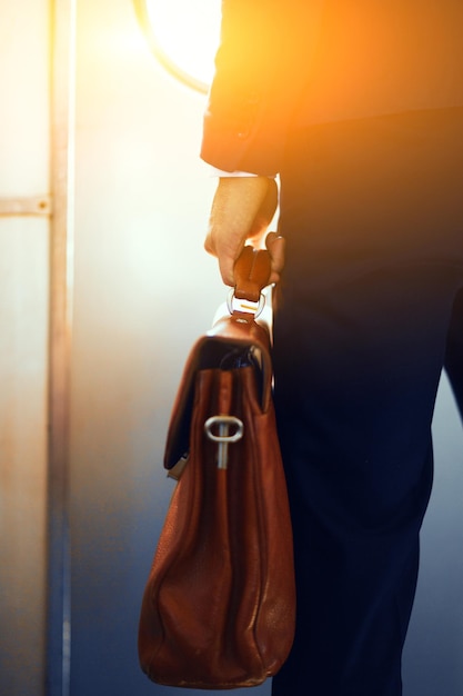 Custodia in pelle marrone nelle mani dell'uomo Immagine ritagliata di uomo d'affari in tuta in piedi nel treno della metropolitana e con in mano una borsa marrone