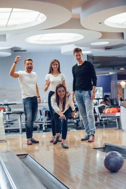 Dai, fai uno sciopero. I giovani amici allegri si divertono al bowling durante i fine settimana