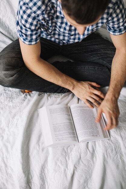 Dall&#39;alto uomo con libro sul letto