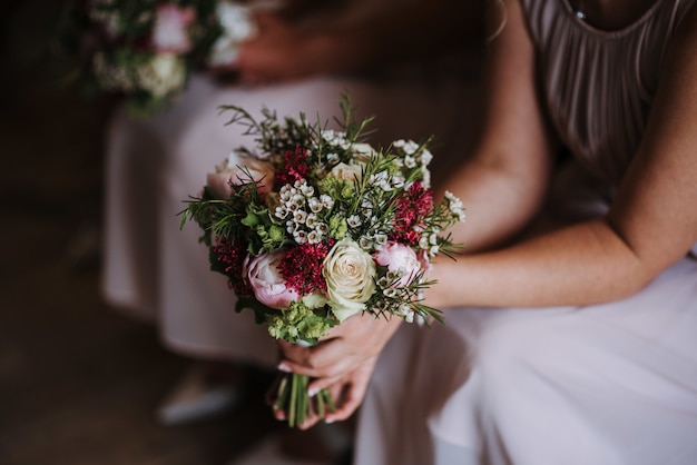 Damigella d'onore che tiene il bellissimo mazzo di rose del giorno del matrimonio