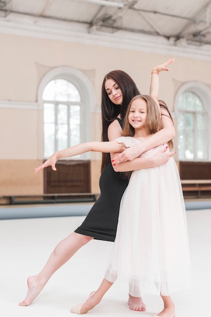 Danzatore di balletto che abbraccia ragazza sveglia sorridente che pratica nello studio di ballo