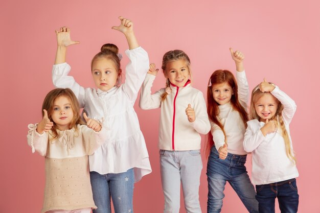 Dare e ricevere regali durante le vacanze di Natale. Gruppo di bambini sorridenti felici divertendosi, celebrando isolato su sfondo rosa studio. Incontro di Capodanno 2021, infanzia, felicità, emozioni.