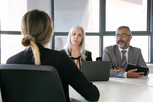 Datore di lavoro serio e responsabile delle risorse umane parlando al candidato di lavoro al colloquio. Vista posteriore, primo piano. Risorse umane e concetto di carriera