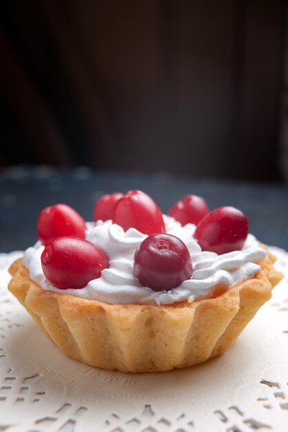 Davanti vista estremamente ravvicinata deliziosa torta con crema e frutti rossi sul biscotto di frutta torta superficie scura