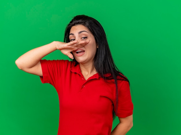 Debole giovane ragazza malata caucasica guardando lato pulendosi il naso con la mano isolata su sfondo verde con spazio di copia