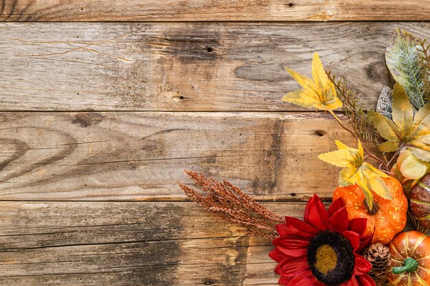 Decorazioni autunnali festive di fiori e foglie di zucche su uno sfondo di legno