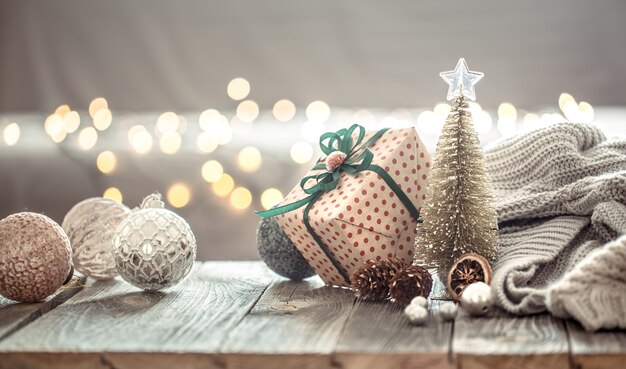 Decorazioni per l'albero di Natale su luci di Natale bokeh in casa sul tavolo di legno con maglione su una parete e decorazioni.