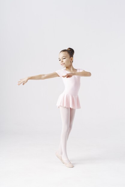 Delicata ballerina ragazza in piedi in posa di balletto su bianco. Generi concetto di sviluppo della personalità.