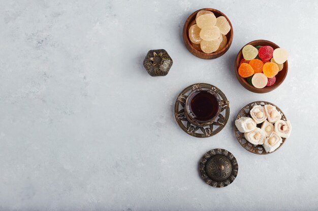 Delizie di marmellata colorata in una ciotola di legno con un bicchiere di tè.