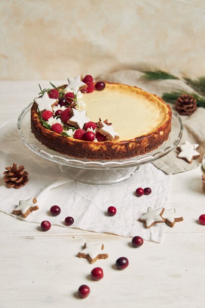 Deliziosa cheesecake natalizia con mirtilli rossi e stelle di biscotti su un tavolo bianco