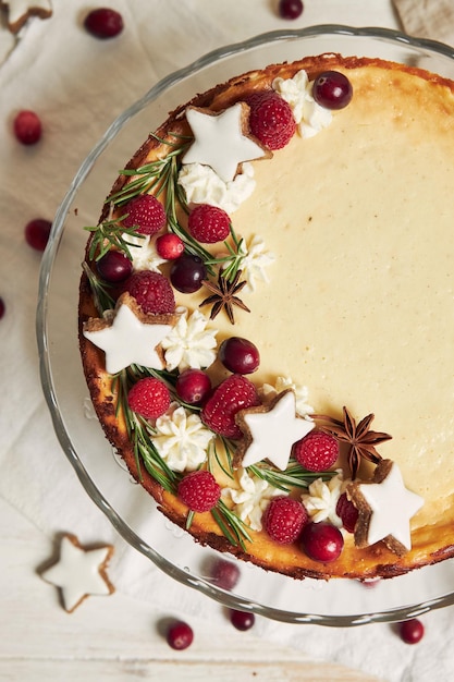 Deliziosa cheesecake natalizia con mirtilli rossi e stelle di biscotti su un tavolo bianco