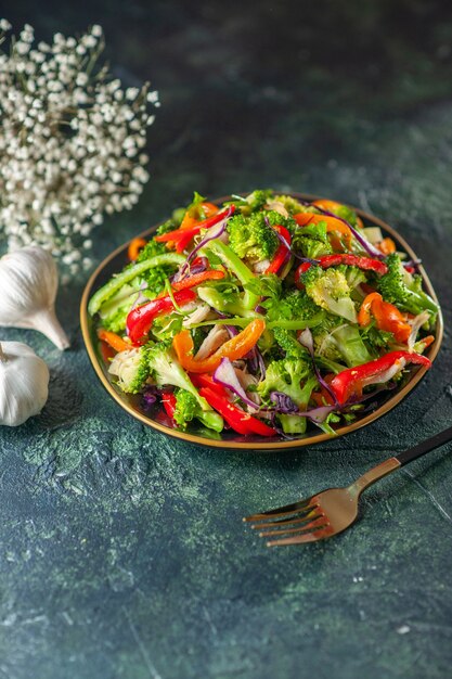 Deliziosa insalata vegana con ingredienti freschi in una piastra forchetta fiori di aglio su sfondo blu sfocato