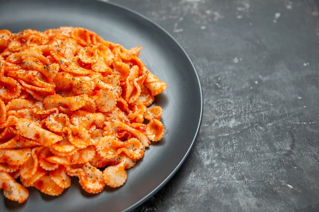 Deliziosa pasta su un piatto nero per cena su sfondo scuro