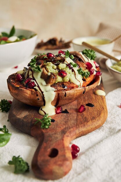 Deliziosa patata dolce al forno sana con guacamole e funghi su un piatto di legno su un tavolo bianco