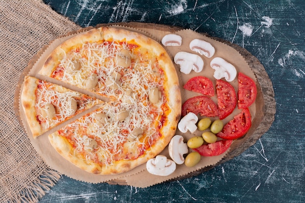 Deliziosa pizza ai funghi con formaggio e verdure fresche su marmo.