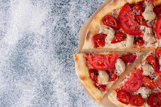 Deliziosa pizza al pollo con pomodori su marmo.