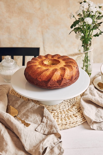 Deliziosa torta ad anello messa su un piatto bianco e un fiore bianco vicino