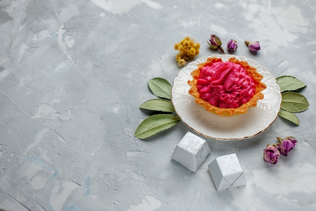 deliziosa torta con crema rosa e cioccolatini sulla scrivania leggera, torta di biscotti dolci alla crema