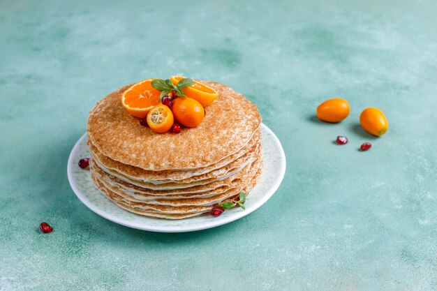 Deliziosa torta crepe fatta in casa decorata con semi di melograno e mandarini.