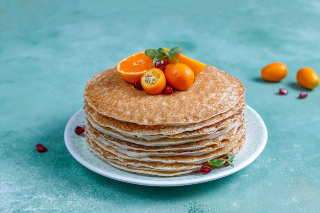 Deliziosa torta di crepe fatta in casa decorata con semi di melograno e mandarini.