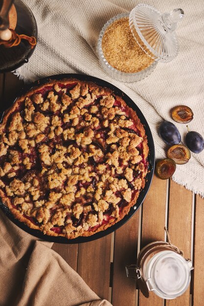 Deliziosa torta di prugne con caffè Chemex e ingredienti con tessuto su un tavolo in legno con tessuto