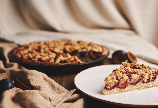 Deliziosa torta di prugne con caffè Chemex e ingredienti con tessuto su un tavolo in legno con tessuto