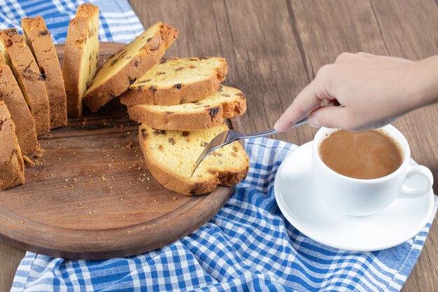 Deliziosa torta su un piatto di legno con una tazza di caffè da parte