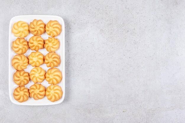 Deliziosi biscotti fatti in casa disposti su un piatto su sfondo marmo.