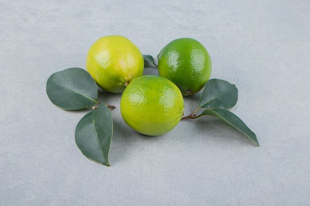 Deliziosi frutti di lime con foglie sul tavolo di pietra.