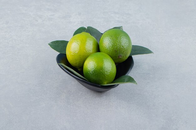 Deliziosi frutti di lime in ciotola nera