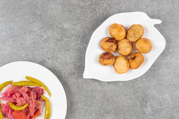 Deliziosi gnocchi fritti sul piatto bianco con sottaceti