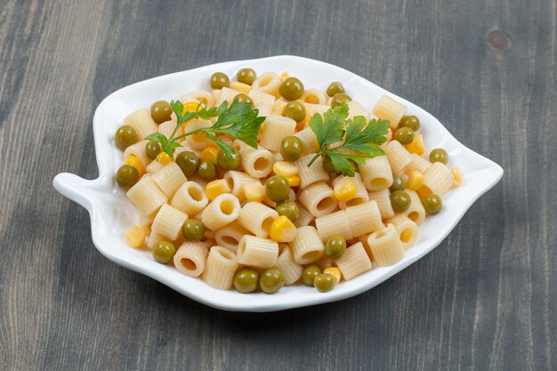 Deliziosi maccheroni con piselli e verdure su un tavolo di legno