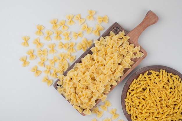 Deliziosi maccheroni crudi sul piatto di legno