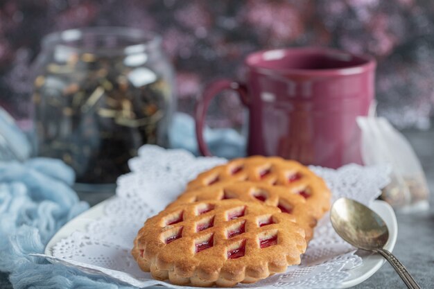 Deliziosi pasticcini con tazza di tè e bastoncini di cannella.