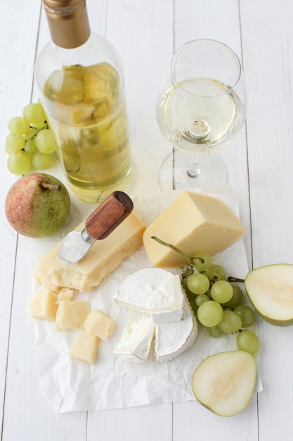 Deliziosi pezzi di formaggio, frutta e vino bianco