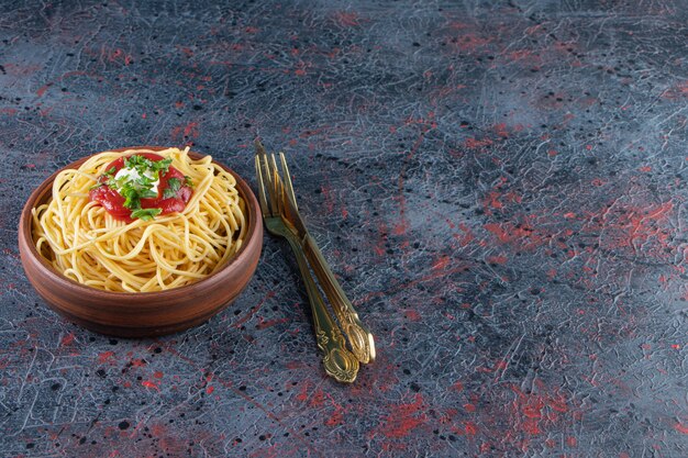 Deliziosi spaghetti al sugo di pomodoro su ciotola di legno con posate.