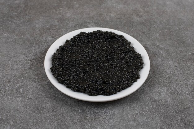 Delizioso caviale nero su ciotola bianca su piatto bianco