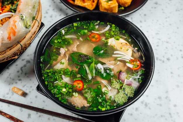 Delizioso cibo vietnamita tra cui Pho ga, tagliatelle, involtini primavera sul tavolo bianco