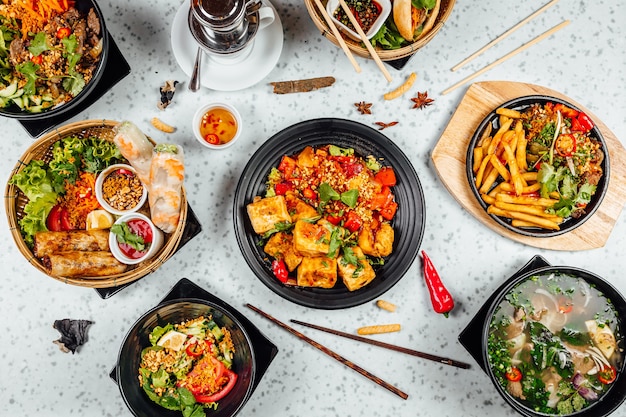 Delizioso cibo vietnamita tra cui Pho ga, tagliatelle, involtini primavera sul tavolo bianco