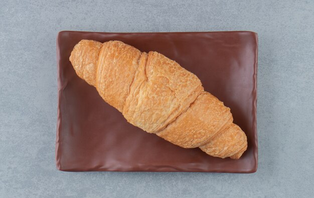 Delizioso croissant sulla piastra, sullo sfondo di marmo. Foto di alta qualità