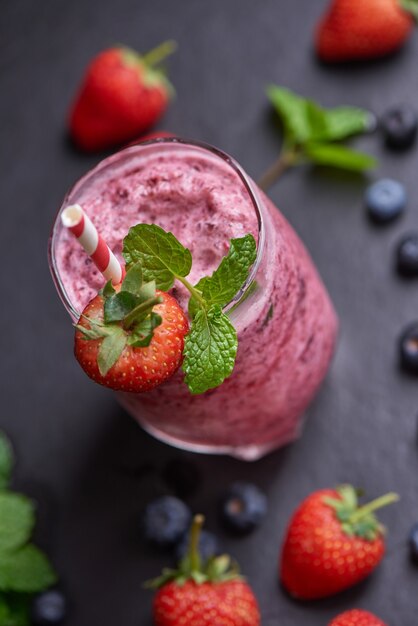 Delizioso frullato di fragole, gelsi e mirtilli guarnito con frutti di bosco freschi e menta in vetro. focalizzazione morbida. bellissimo antipasto lamponi rosa, benessere e concetto di perdita di peso.