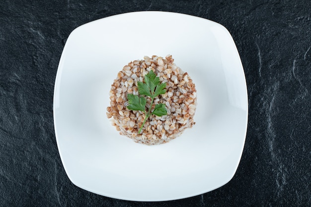 Delizioso grano saraceno con verdure su un piatto bianco