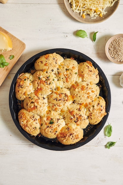 Delizioso pane per pizza con bolle di formaggio con ingredienti e formaggio su un tavolo bianco