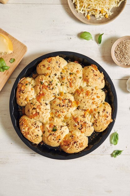 Delizioso pane per pizza con bolle di formaggio con ingredienti e formaggio su un tavolo bianco